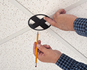 person tracing cutout for box on ceiling tiles
