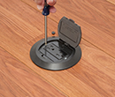 person installing cover onto floorbox installed in wooden floor