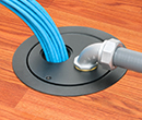 floor box in wooden floor with conduit entering box and bundle of cables exiting box