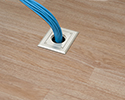 floor box in wooden floor with bundle of cables routed into floor box