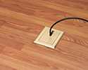 floor box in wooden floor with device plugged in and routed through slotted cover