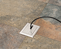 floor box in tiled floor with device plugged in and routed through slotted cover