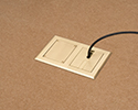 two gang floor box in wooden floor with device plugged in