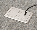 two gang floor box in carpeted floor with devices plugged in