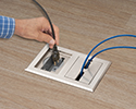 person plugging device into floor box receptacle