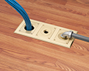 three gang floor box in wooden floor with cables running through box