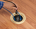 person plugging device into floor box receptacle