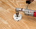 person using hole saw on subfloor