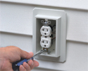 person installing receptacle in siding outlet box with screwdriver