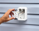person putting wired receptacle into siding outlet box