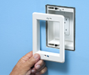person adding trim plate to recessed TV box